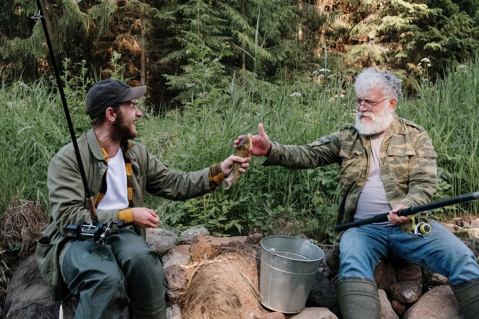 Two anglers sharing a moment beside a forest stream